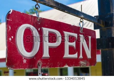 Open business old red and white vintage sign hanging from black metal pole