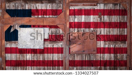 A closeup of an old warehouse gate with the national flag of Liberia. The concept of export-import Liberia, storage of goods and national delivery of goods. Flag in grunge style