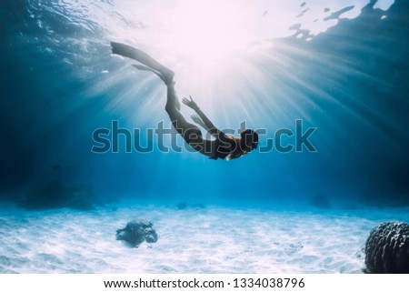 Young woman free diver glides over sandy sea with fins. Freediving in blue ocean Royalty-Free Stock Photo #1334038796