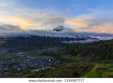 the view from the viewing post is Dieng with cloud-covered morning sun, mountain ranges and Sumbing mountains and villages in the distance