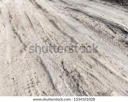 Tyre track and human footprint on sand texture background. Traces of off-road tires. Cracked earth on country road with traces of tires, cars, cracks and dirt. To use as background