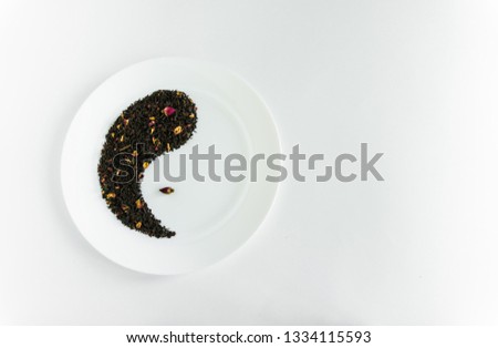 Flower tea with red roses in the form of yin-yang on a white plate