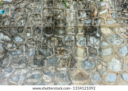 Wall consisting of old masonry with concrete, with water and algae stains
