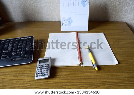 Calculator, notebook, pen, calendar and keyboard on the table.