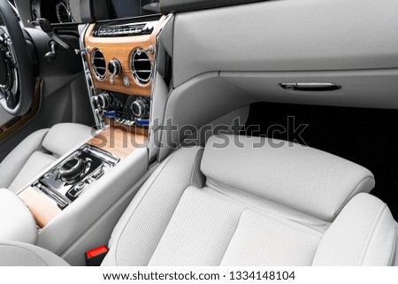 Modern luxury car white leather interior with natural wood panel. Part of leather  seat details with stitching. Interior of prestige modern car. White perforated leather. Car detailing. Car inside
