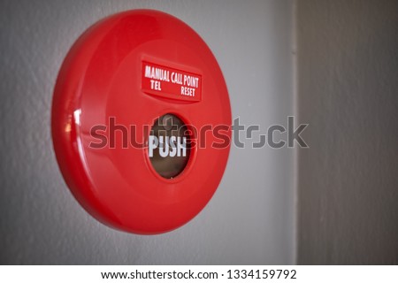 Close up of red manual fire alarm activation on gray wall. The use of a pull station or call point will sounds the evacuation alarm for the relevant building or zone.  Fire detection and alarm system.