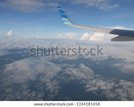 Airplane wing in the blue and white sky. 