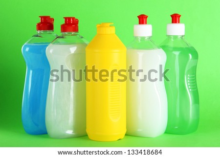Bottles of dishwashing liquid on color background