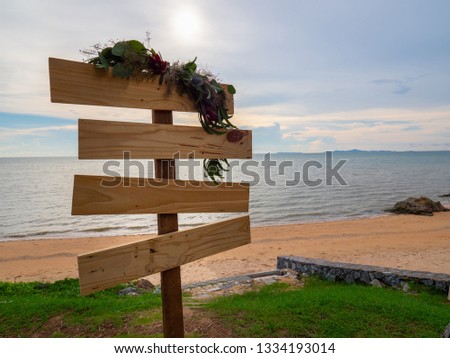 Blank wooden sign board decorate by some leaves and a little flower for wedding ceremony at beach.