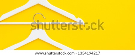 Creative top view flat lay white wooden hangers isolated bold yellow background with copy space minimalism style. Template fashion feminine blog social media sale store promo design shopping concept