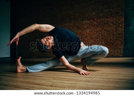 Young man doing yoga in big bright training gym