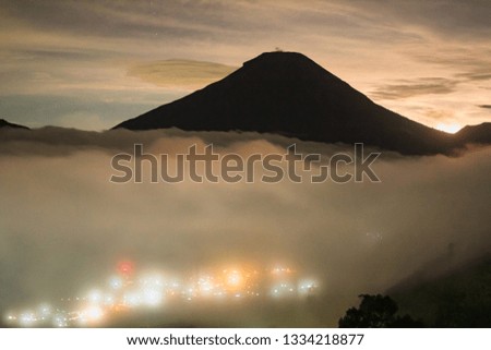 the view from the Dieng observation post at night, the fog covered the village with the background of the Sumbing mountain silhouette
