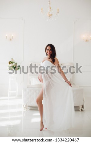 View from side of pregnant woman in beautiful white dress