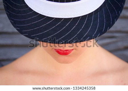 Young lady with half face hidden under the black hat