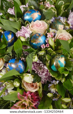 Decorated Eggs For Easter. Alternative decoration. Dyed eggs in green, blue, turquoise and golden on bouquet of flowers background.