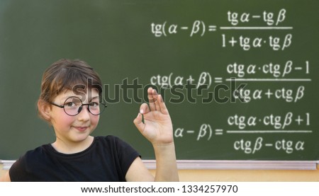 Little girl solves the problem on a blackboard. Wunderkind