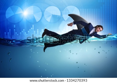 Businessman with shark fin swimming in water