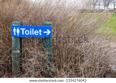 Toilet sign amongst bushes outdoor