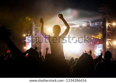 Photo of a crowd, people enjoying rock concert, raised up hands and clapping of pleasure, active night life concept.