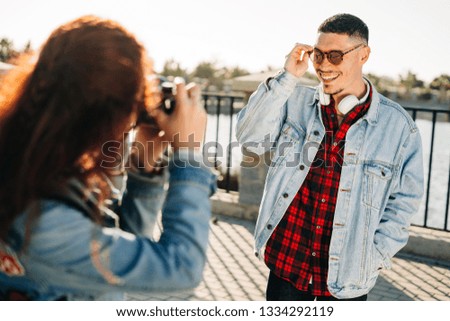 Young photographer woman making photo to young man. Happy Couple on holiday.