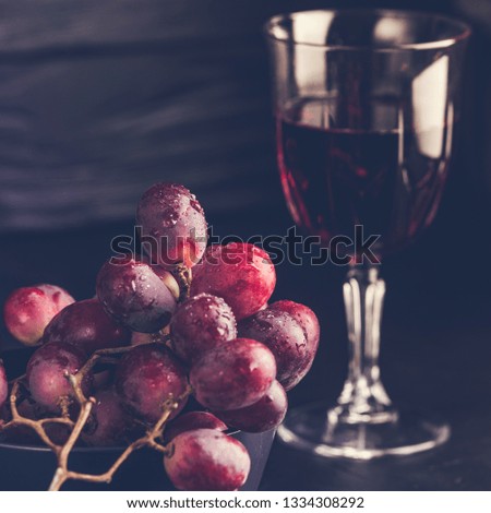 Purple grapes with water drops, grape juice in a glass jar, dark picture. Selected focus, macro
