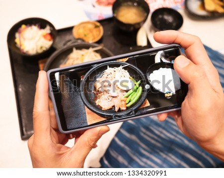 Happy time of man hand using smart phone taking photo which take a picture set of food in a Japanese restaurant