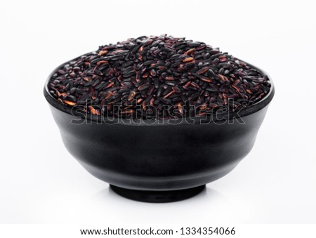 Black bowl of raw organic black venus rice on white background. 
