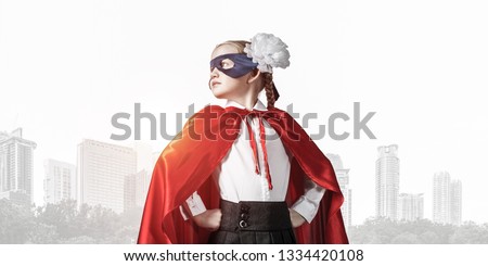 Little confident child in mask and cape plays cool superhero