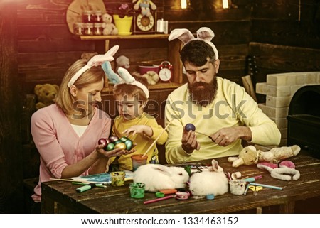 Happy easter! Mother, father and her child enjoy painting Easter eggs.