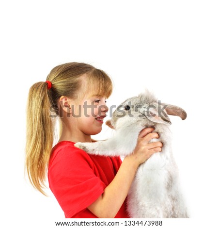 Little girl holding rabbit .