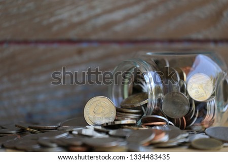 The coin of Thailand in the glass jar that is upside down Old wooden wall as background selective focus and shallow depth of field
