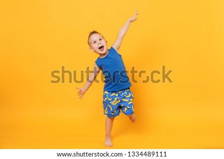 Little cute kid boy 3-4 years old wearing blue beach summer clothes isolated on bright yellow orange wall background, children studio portrait. People, childhood lifestyle concept. Mock up copy space Royalty-Free Stock Photo #1334489111