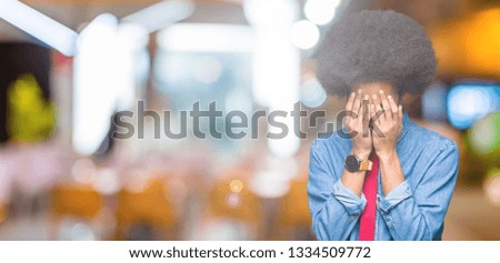 Young african american business man with afro hair wearing glasses and red tie with sad expression covering face with hands while crying. Depression concept.
