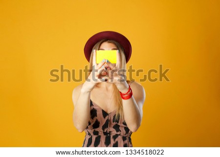 Happy tourist woman holding travel yellow case and credit card. Studio portrait. Vacation concept.