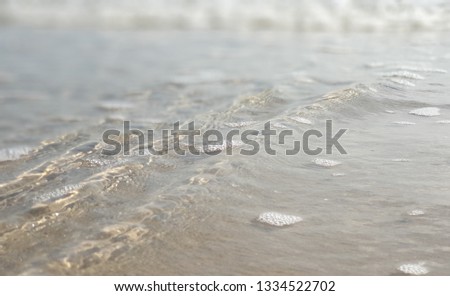 blurred picture of sea water and wave bubble on sand with copy space 