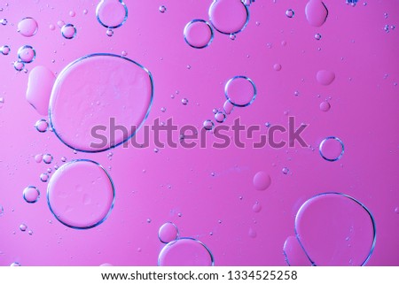 Beautiful and fantastic macro photo of water droplets in oil with a violet background.