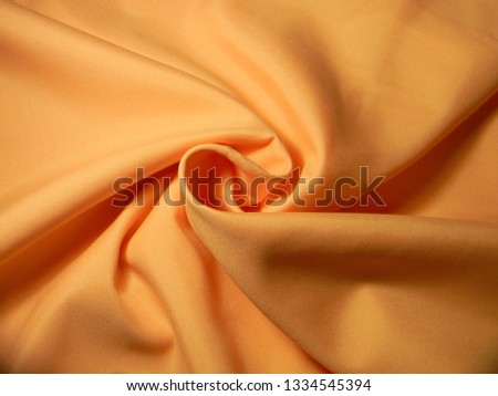 Peach colored plain cotton wavy fabric. Texture, background. template. Lightweight fabric for curtains or bed linen. Poplin, coarse calico, staple, satin, chintz. Folds of fabric. Textile. Material
