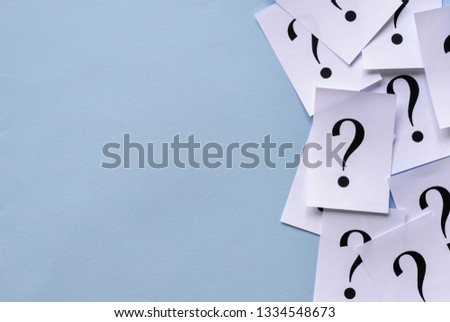 Side border of printed question marks on loose sheets of white paper overlaid together with lateral copy space on a blue background