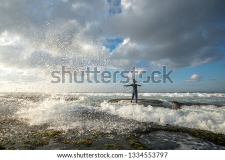 Strong woman outstretched arms at seaside mossy coral reef