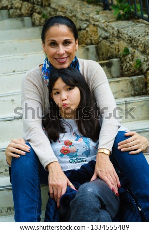 Mother with pre teenage daughter outdoor portrait.