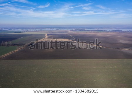 Aerial view of farmland and river during sunny spring day.