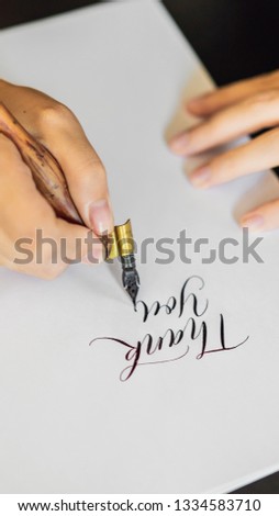 Calligrapher hands writes phrase on white paper. Phrase - Thank you. Inscribing ornamental decorated letters. Calligraphy, graphic design, lettering, handwriting, creation concept VERTICAL FORMAT for