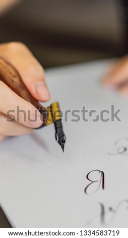 Calligrapher hands writes phrase on white paper. Inscribing ornamental decorated letters. Calligraphy, graphic design, lettering, handwriting, creation concept VERTICAL FORMAT for Instagram mobile