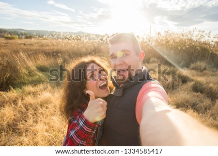 Travel, holidays and nature concept - Happy couple taking a selfie at a field