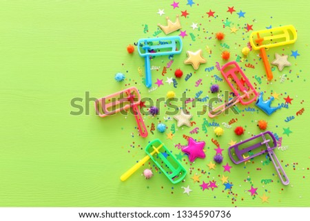 Purim celebration concept (jewish carnival holiday) confetti and noisemaker over wooden green background