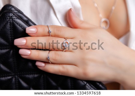 Closeup beautiful brunette girl with long hair in silver jewelry earrings, rings, bracelet and necklace in decollete. Сoncept of gentle, elegant, delicate, romantic jewelry, bijouterie on model