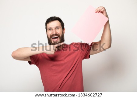 Young bearded man with blank pink banner. Smiling man holding advertising sheet, copy space, isolated 