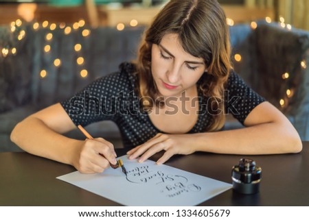 Calligrapher Young Woman writes phrase on white paper. Dream big, set goal, take an action. Inscribing ornamental decorated letters. Calligraphy, graphic design, lettering, handwriting, creation