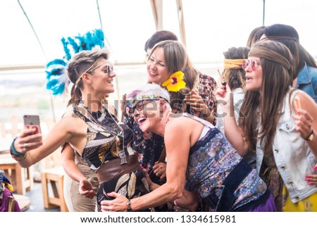 hippy group of caucasian beautiful females looking a smartphone to see a picture or internet results on the web. nice attractive people stay together in happy leisure activity with friendship