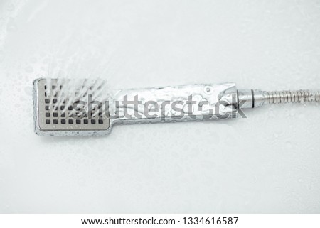 Silver Hand shower with hose flowing water isolated on white background